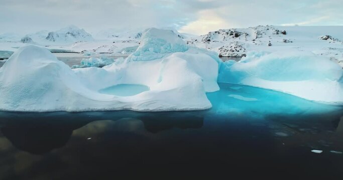 Global warming, melting icebergs in Antarctica. Glacier with melted cavity floating in blue ocean water. Polar climate change at sunny winter day. Cinematic ecology scene. Close up shot zoom in