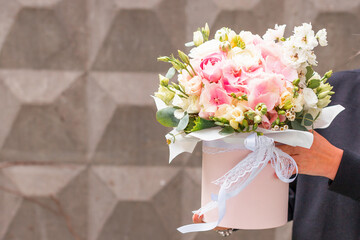 Flower arrangement in a purple hat box was created by a florist for a wedding gift. Flower bouquet of purple hydrangea, white freesia, pink ranunculus asiaticus, eustoma flowers, roses and eucalyptus