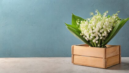 box with lily of the valley flowers on table against light blue background with space for text