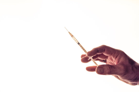 Hand eines Mannes hält Impfspritze vor weißem Hintergrund, Studioaufnahme, Deutschland