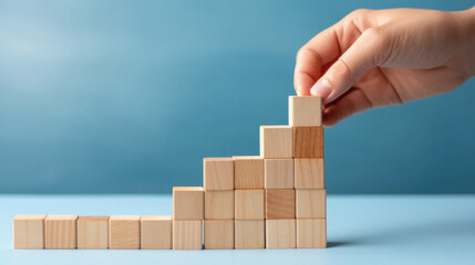 Wooden block stacking as step stair on blue background, business growth concept