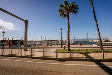 Santa Margarita, Spain - January 24, 2024 -  road leading towards "La Linea" and "Gibraltar" with palm trees, traffic signs, cars, a marina, and a mountain in the background.