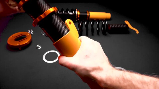 tuning car suspension, coilovers, shock absorbers and front springs in yellow and gold color for a sports drift car on a dark background assembly by the hands of a car mechanic