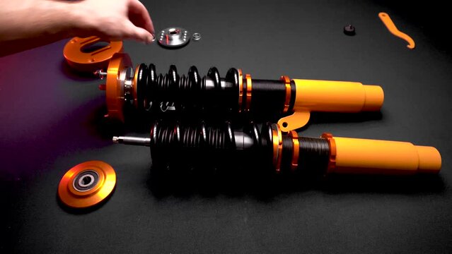 tuning car suspension, coilovers, shock absorbers and front springs in yellow and gold color for a sports drift car on a dark background assembly by the hands of a car mechanic
