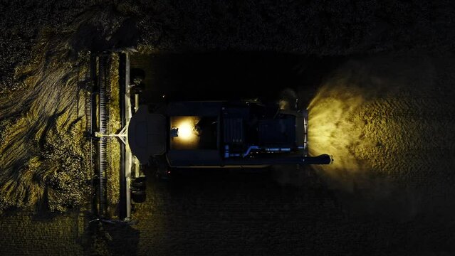 Combine harvester harvesting corn in the dark top view