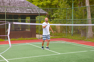 man plays badminton outdoors in the fresh air, throws a shuttlecock and holds a racket, an island in the Maldives, active recreation and sports