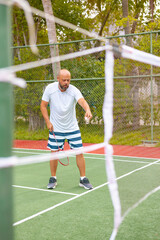 man plays badminton outdoors in the fresh air, throws a shuttlecock and holds a racket, an island in the Maldives, active recreation and sports