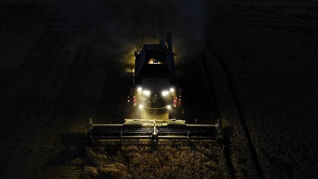 Combine harvester harvesting corn in the dark aerial view