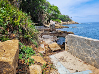 A rugged stone walkway hugs the shoreline Playa La Angosta, Acapulco