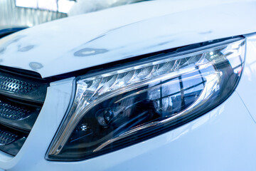 close-up of the headlights of a beautiful expensive white car at a service station