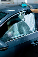 the auto mechanic thoroughly washes the car glass before gluing the protective film detailing