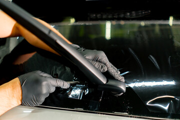 close-up, the master applies a protective film for tinting to the glass dries it car detailing