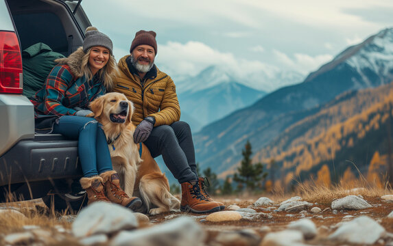 Middle aged beautiful couple with dog traveling by car in the mountains, summer vacation and adventure.