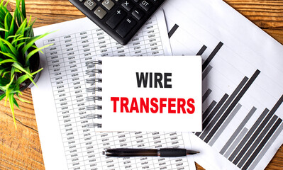 WIRE TRANSFERS text on a notebook with pen, folder on a chart background