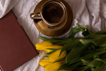 Morning, coffee and tulips. On a white bed. Romance.