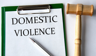 DOMESTIC VIOLENCE - words on a white sheet on a white background and a judge's gavel