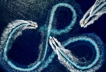Aerial top view of a group of motor speed boats driving circles of waves and bubbles on the ocean