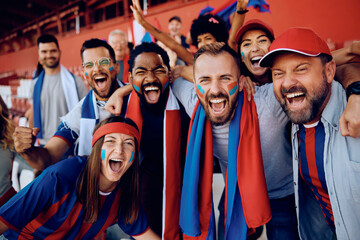 Cheerful sport fans celebrating victory of their favorite team at stadium and looking at camera. - obrazy, fototapety, plakaty