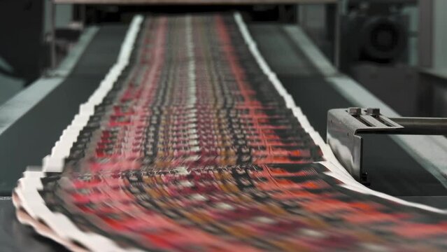 Factory Press: High-Speed Printing of Red Newspapers on Conveyor Belt"