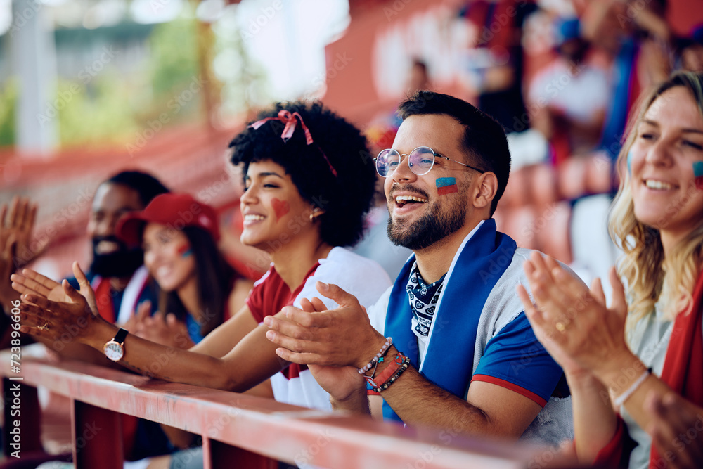 Wall mural Multiracial group of happy fans applauding while watching sports match at stadium. - Wall murals