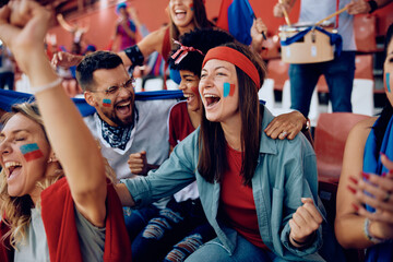 Cheerful sports fan and her friends celebrating during match at stadium.