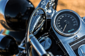 Close-up of a vintage motorcycle steering wheel and speedometer.