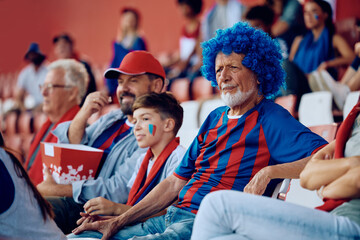 Senior man feeling displeased while watching his favorite sport team loosing  match at stadium.