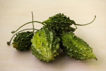 Fresh green fruit or vegetable Bitter gourd or Bitter melon on a wooden background. Also known as Momordica charantia, karela, korola, or balsam pear. It is locally known as Korola in Bangladesh.