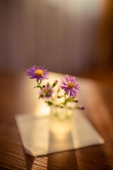 Little vase with delicate purple flowers chrysanthemums on a wooden table.