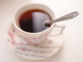Spoon in a cup of drink. Cup of tea on a saucer in blur on a whi