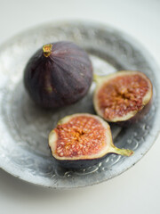 One whole fig and the second cut in half on a white table. Selective focus.