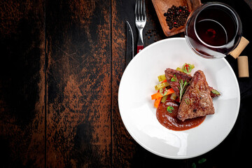 Beef liver stewed with demiglas sauce and served with vegetables on a white plate. Top view and copy space