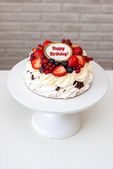 Pavlova cake with whipped cream cheese, chocolate sauce and fresh berries on grey background. Beautiful cake for the Birthday party