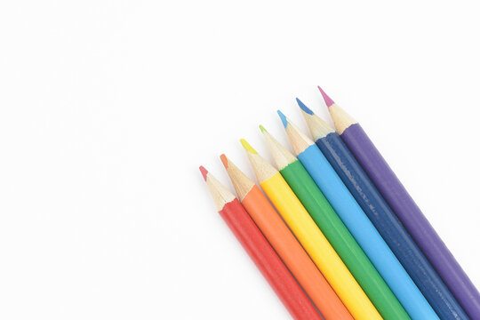 A set of wooden pencils in colours of the rainbow.  Red, orange, yellow, green, blue, indigo, and violet. Arranged in a line on white background. Close Up.
