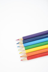 A set of wooden pencils in colours of the rainbow.  Red, orange, yellow, green, blue, indigo, and violet. Arranged in a line on white background. Close Up.