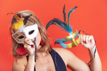 Woman trying on colorful Venetian masks, isolated on an orange background