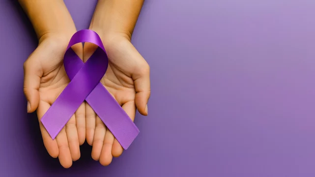 Two hands holding awareness ribbon, purple background, top view, copy space on the right