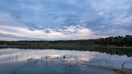 This image is a serene portrayal of a wetland at twilight. The reflection of the twilight sky, with...