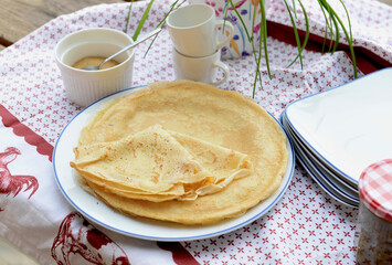 traditional french homemade pancakes  in a plate served on a table with red and white tablecloth