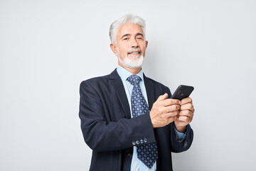 Naklejka premium Portrait of elderly businessman in suit holding mobile phone in hand with happy smiling face. Person with smartphone isolated on white background.