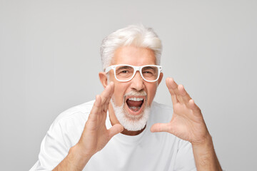Portrait of senior man in white shouting loudly with hands, news, palms folded like megaphone isolated on white background