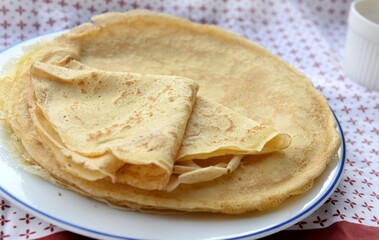 traditional french pancake homemade- folded crepe in a plate on a red and white tablecloth