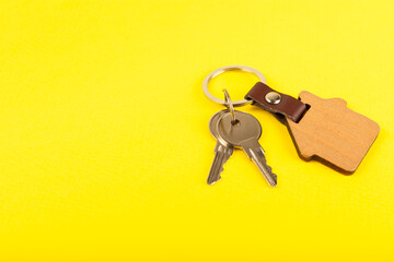House keys with a keychain in the shape of a house on a colored background.Design element.Real estate and insurance concept.Copy space. Rent, sale or purchase of real estate.
