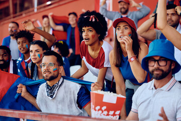 Multiracial group of spectators watching sports match on stadium. - obrazy, fototapety, plakaty