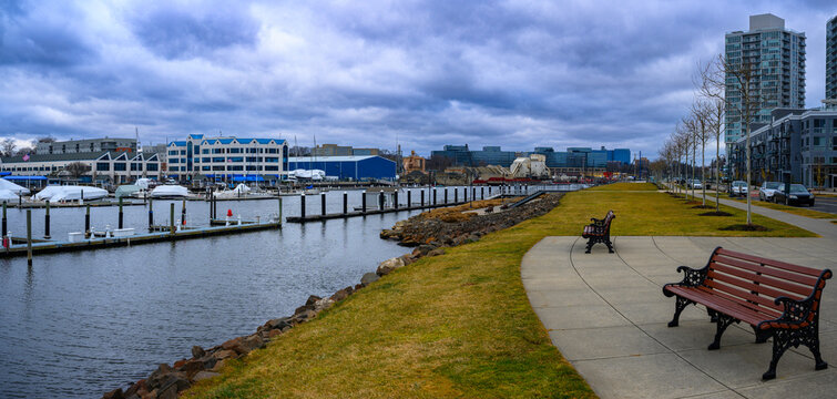 Stamford City Harbor Point Landscape with tall office buildings, park benches, boardwalk footpaths, and moored boats at the dock on a dramatic stormy winter in Connecticut