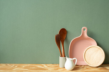 Kitchen ceramic dish plate, coaster, cutlery holder on wooden shelf. green wall background - obrazy, fototapety, plakaty