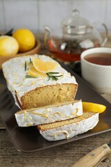 Tasty lemon cake with glaze and tea on wooden table, closeup