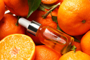 Bottle of tangerine essential oil with fresh fruits, closeup