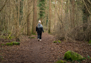 middle-aged white woman with brown hair, wearing a black sweater and a beige hat, in an Irish winter forest.