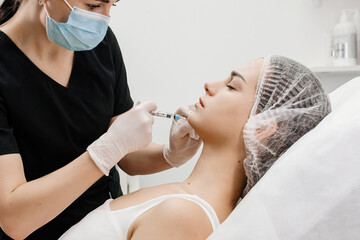 Injection procedure. The cosmetologist slowly and carefully injects filler into the client’s...